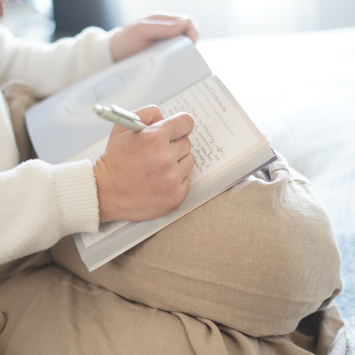 A person writing in their 365 intention journal with a smooth black pen