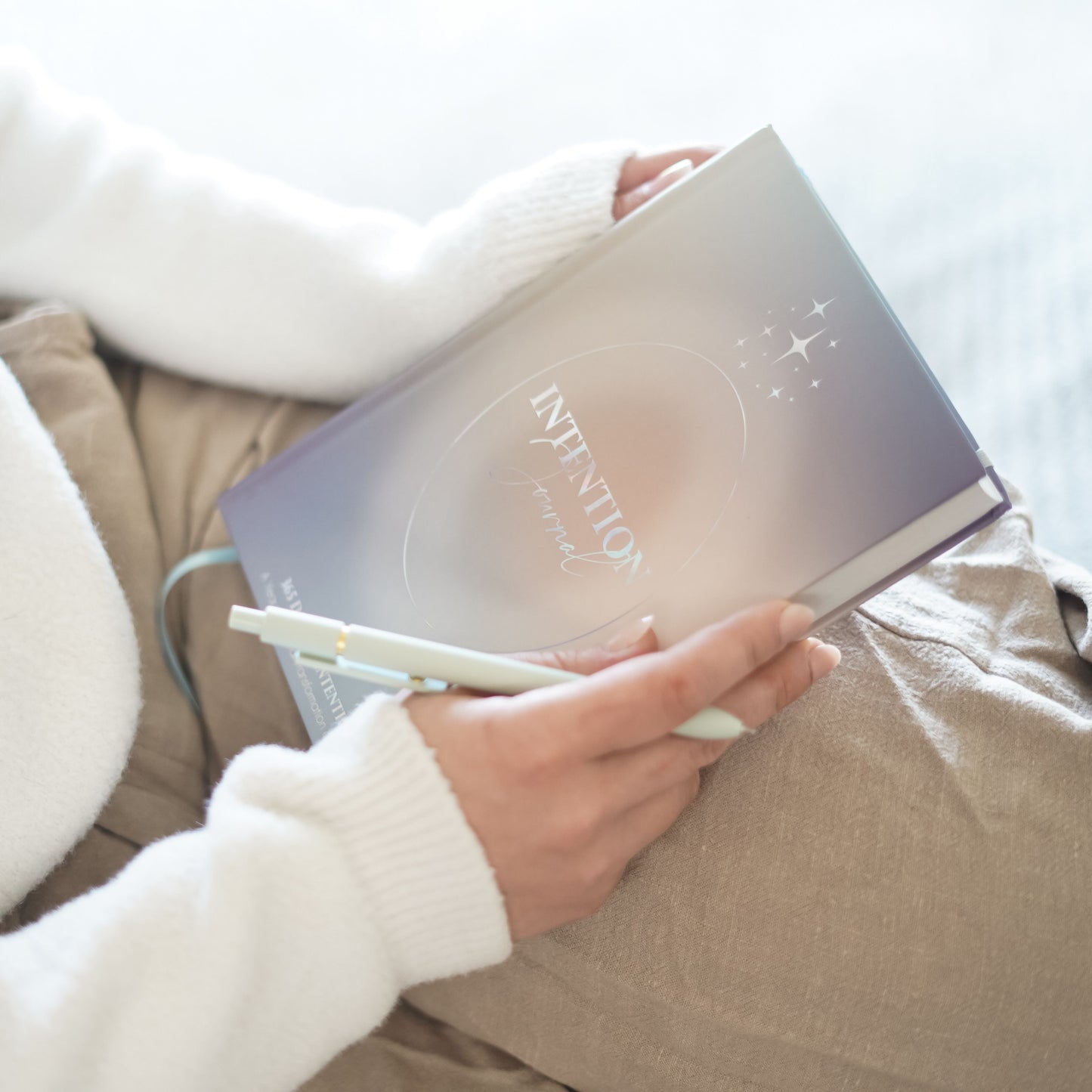 A person gently holding the 365 intention journal with both hands, showing its sleek cover and minimalist design