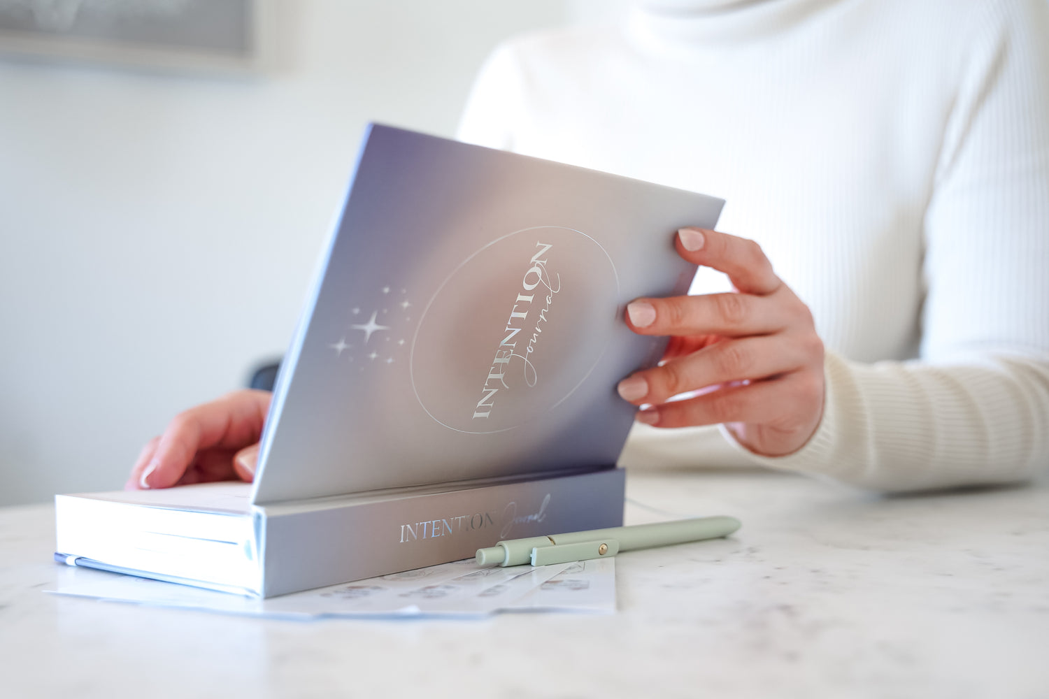 A person gently opening the 365 intention journal showing its minimalist design