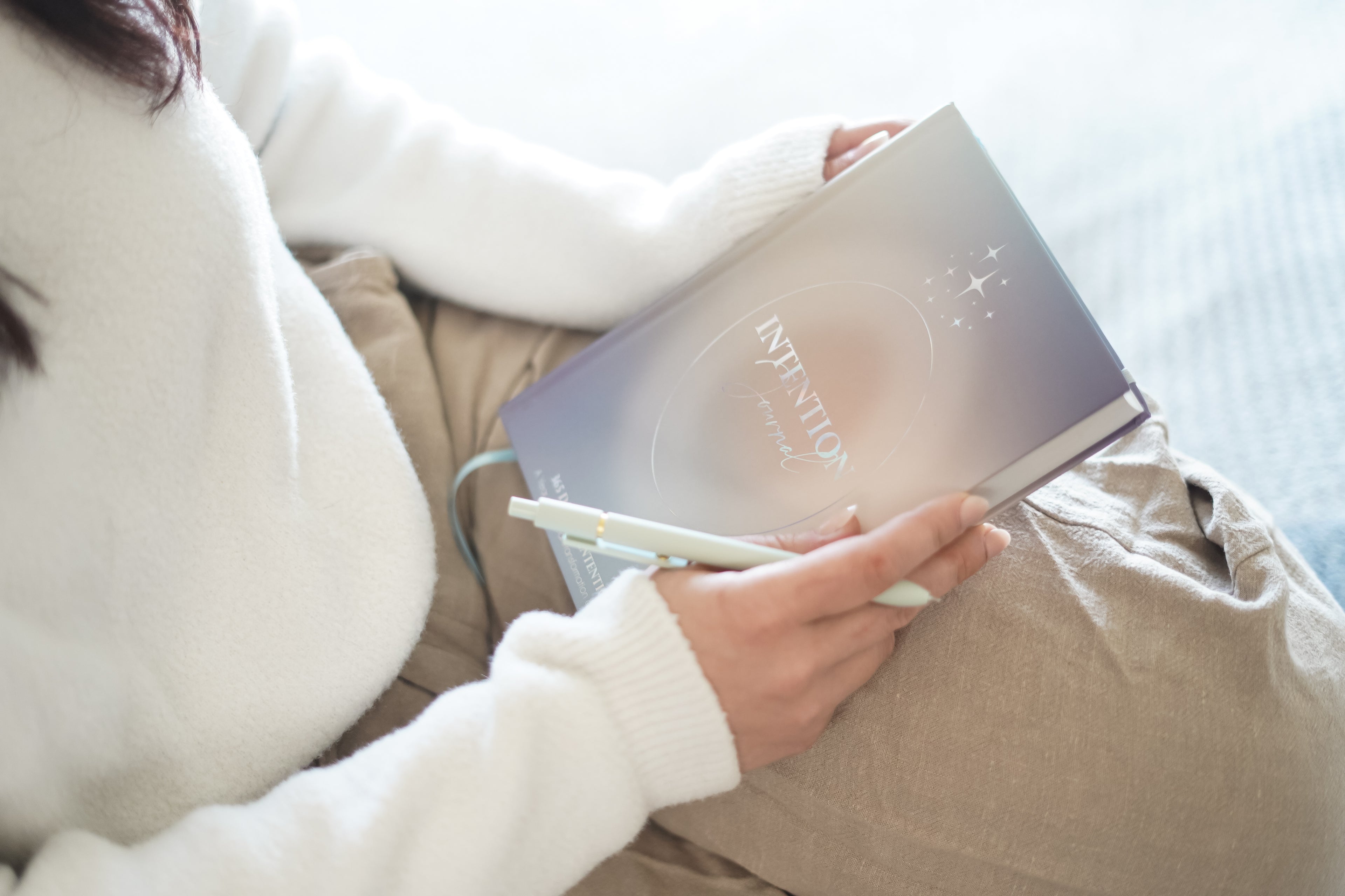 A person gently holding the 365 intention journal with both hands, showing its sleek cover and minimalist design.