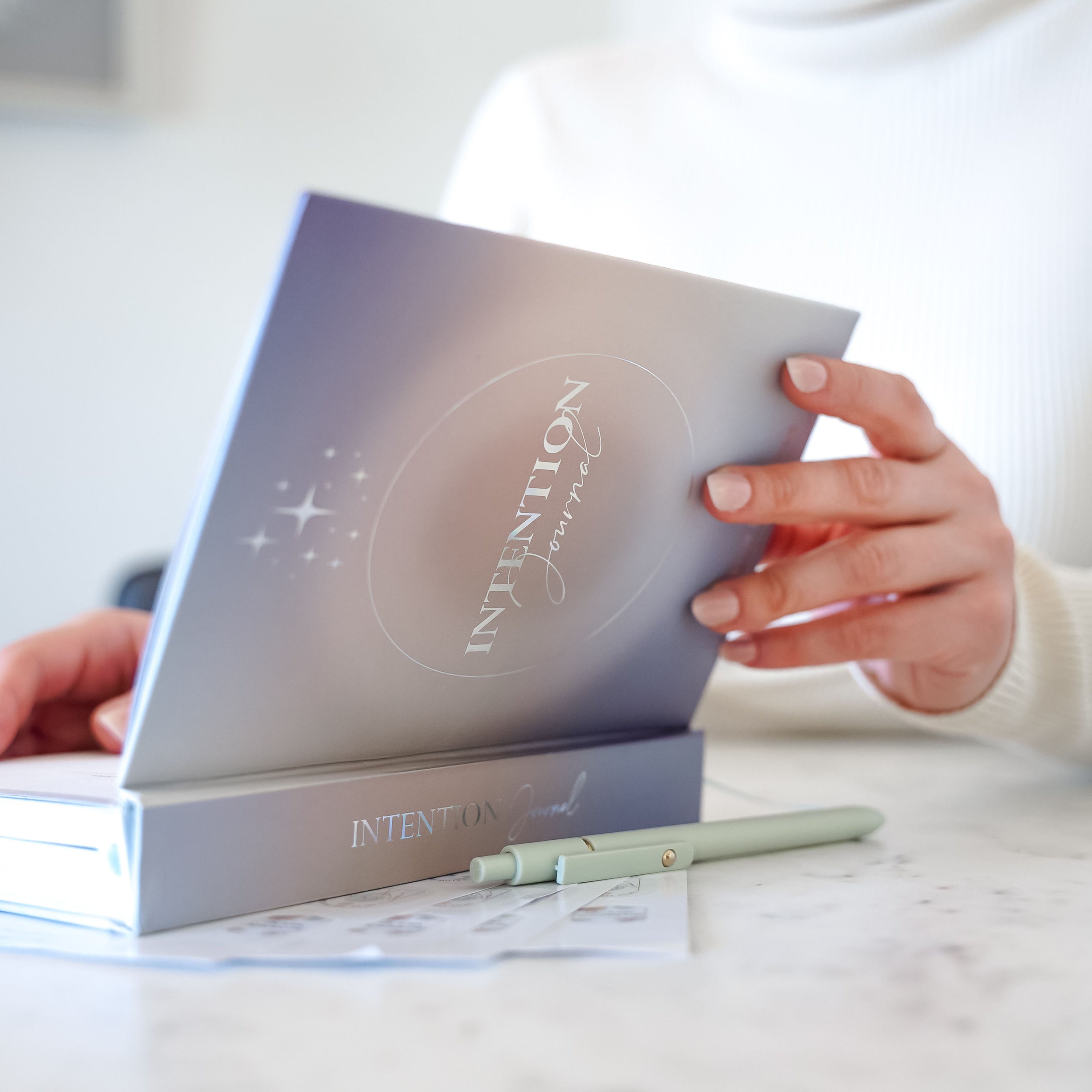 A person gently holding the 365 intention journal with both hands, showing its sleek cover and minimalist design