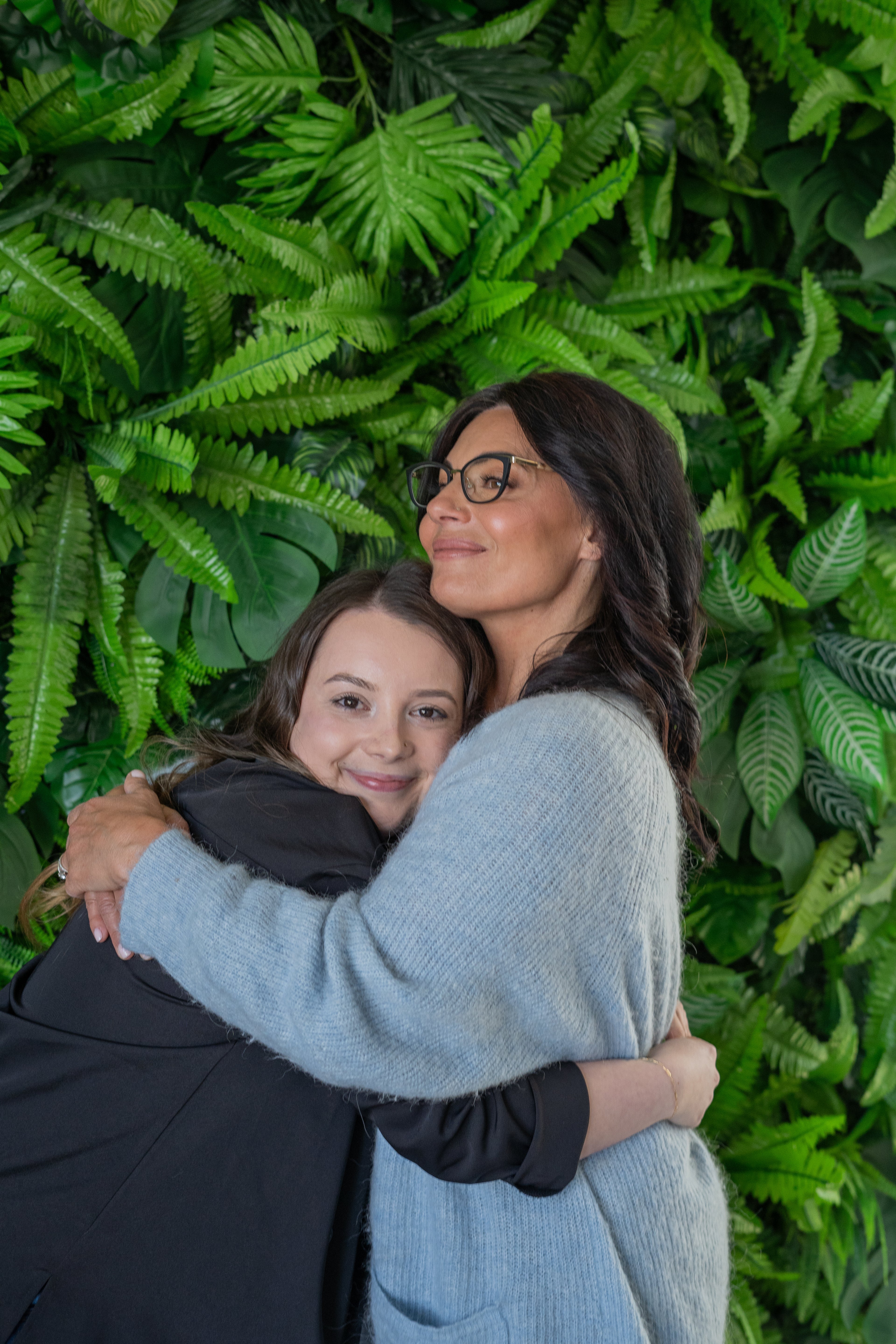 Dr. Katie Branter warmly embraces her niece, both smiling against a green leaf backdrop
