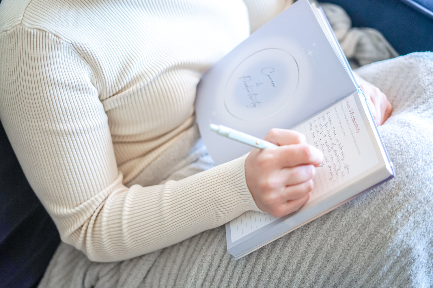 A person writing in their 365 intention journal with a smooth black pen